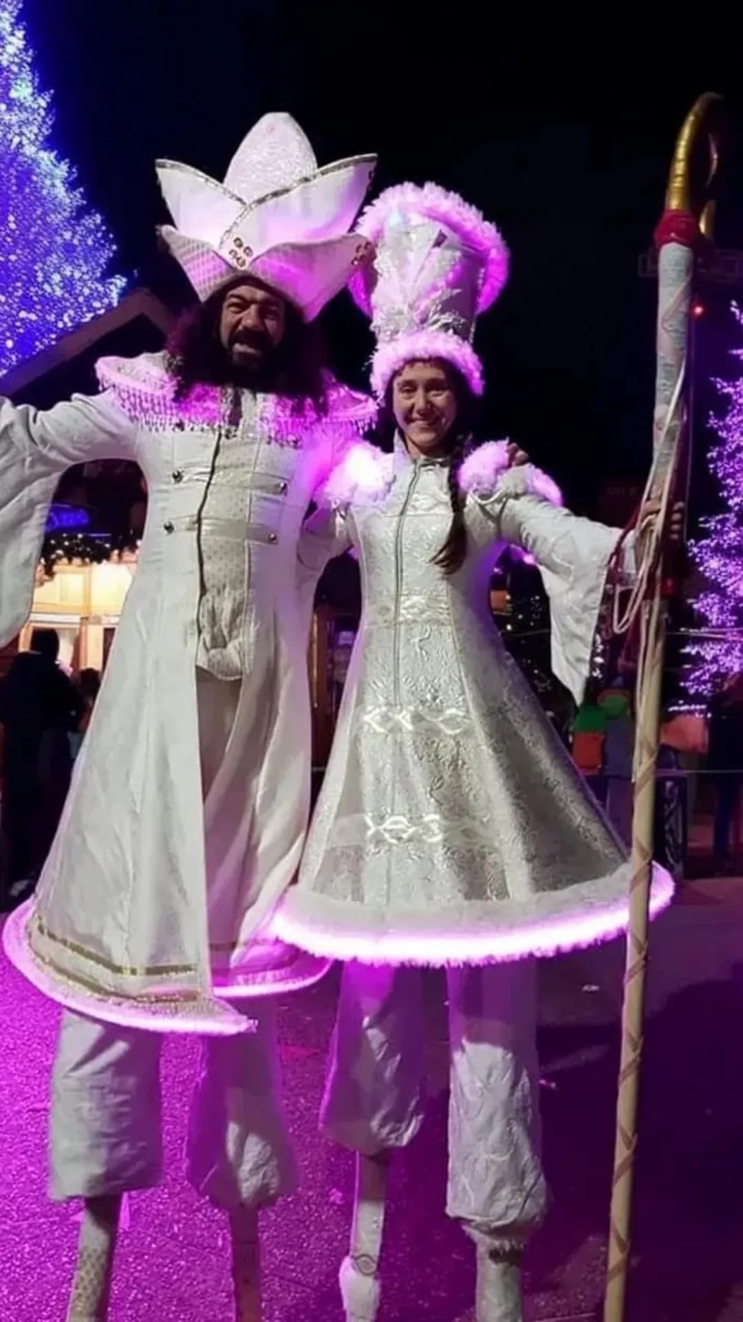 Deux échassiers lumineux en costume blanc lors d’un spectacle de rue de Noël
